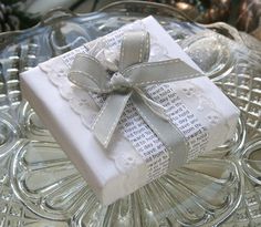 a gift wrapped in white paper on top of a glass plate