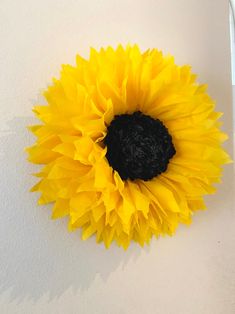 a large yellow sunflower sitting on top of a white wall