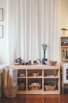 a table with baskets and toys in front of a curtain