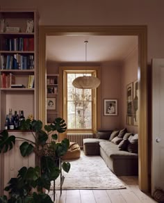 a living room filled with lots of furniture and bookshelves next to a window