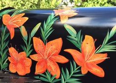 an orange flower painted on the side of a black mailbox with green leaves and flowers