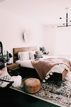 a bed room with a neatly made bed next to a window and a rug on the floor