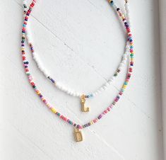 This adjustable seed bead initial necklace is a must have! Danity and cute it's the perfect summer accessory! Adjustable clasp makes it so anyone can wear it however you like! Rainbow bead necklace pattern may vary. How to order Choose a style of necklace Choose your initial Add to cart Adjustable White Charm Necklaces With Letter Beads, White Adjustable Charm Necklace With Letter Beads, Cute Summer Beaded Necklaces With Letter Beads, Cute White Beaded Necklaces With Tiny Beads, Cute White Beaded Necklaces With Letter Beads, Cute Summer Necklace With Letter Beads, Cute White Beaded Necklace With Letter Beads, Cute White Beaded Necklace With Tiny Beads, Playful White Necklace With Letter Beads