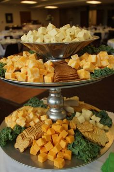 a three tiered platter filled with cheese and crackers on top of a table