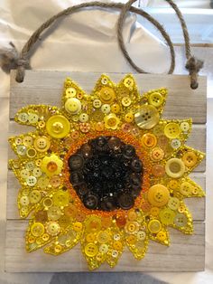 a sunflower made out of buttons on a piece of wood