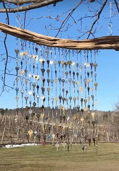 a wind chime hanging from a tree in the middle of a field with snow on the ground