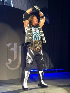 a man standing on top of a wrestling ring holding his hands up in the air