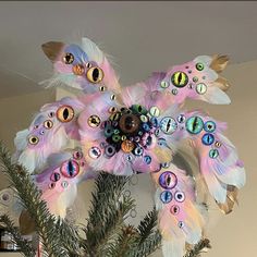 a christmas tree decorated with pink feathers and eyeballs on it's branches in front of a wall