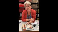 a woman sitting at a table in front of a card board with pictures on it