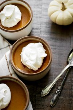 three bowls filled with dessert sitting on top of a table next to two pumpkins