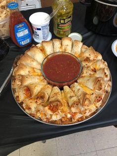 a pizza pie on a table with sauce and condiments for dipping in the middle