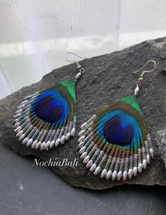 peacock feather beaded earrings on top of a rock