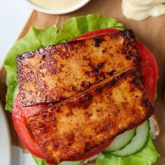 two pieces of grilled fish on lettuce with tomato and cucumber