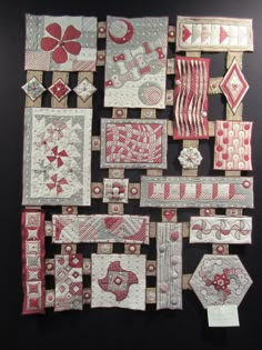 many different pieces of fabric are arranged on a black surface with red and white designs