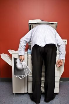 a man standing in front of a printer with his back to the camera