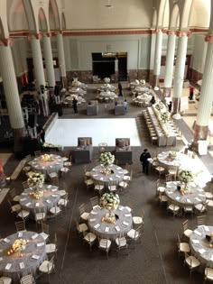 tables and chairs are set up in the middle of a large hall with columns on both sides