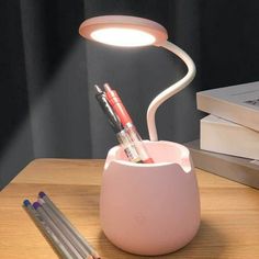 a desk lamp that is on top of a table next to some books and pencils