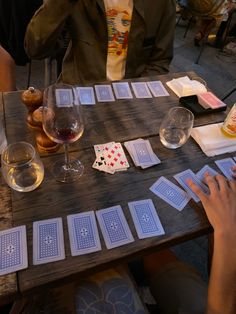 people sitting at a table with playing cards and wine glasses on top of the table