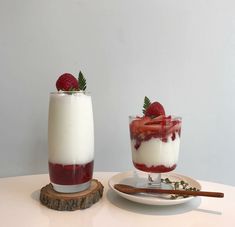 two desserts with strawberries and yogurt are sitting on a table next to each other