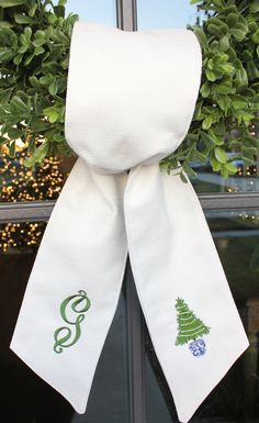 a white scarf hanging on a window sill with green christmas trees and blue berries