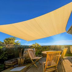 the sun is shining on an outdoor patio with chairs and table under a shade sail