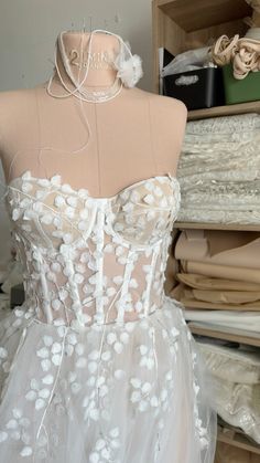 a mannequin wearing a white dress with flowers on it's bustle