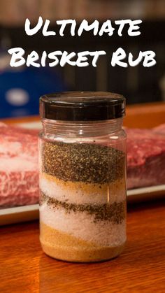 a jar filled with spices sitting on top of a wooden table next to a steak