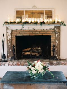 a fireplace with candles and flowers on it