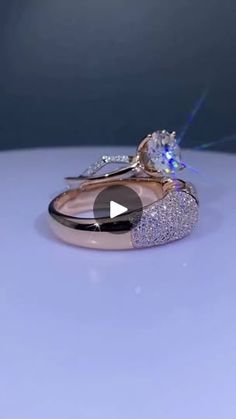 two wedding rings with diamonds on them sitting on top of a white table next to each other