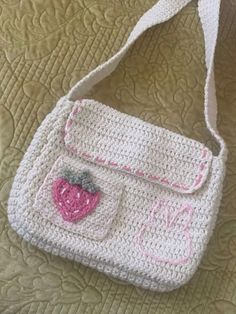 a crocheted purse sitting on top of a bed next to a white pillow