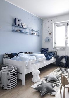 a child's bedroom with blue walls and white furniture, including a toddler bed