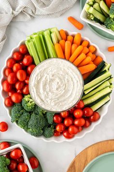 a platter filled with vegetables and dip surrounded by small bowls of veggies