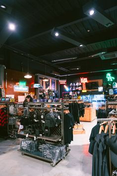 the inside of a clothing store with clothes on racks