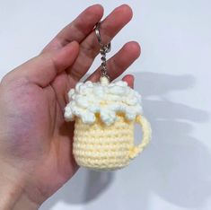 a hand holding a crocheted keychain shaped like a mug