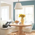 a dining room table with four chairs and a vase on the table in front of it