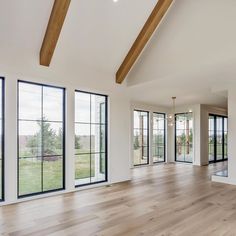 an empty living room with wood floors and large windows on the side of the wall