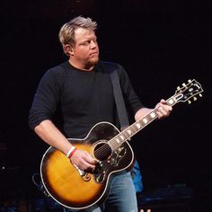 a man holding an acoustic guitar on stage