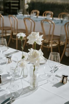 the table is set with white flowers and empty wine glasses for guests to sit at