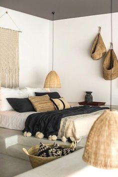 a bedroom with wicker hanging from the ceiling and pillows on the bed in front of it