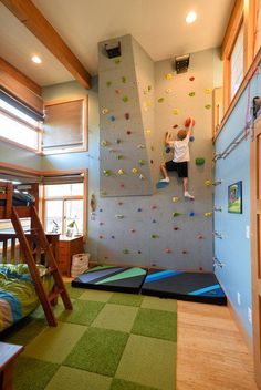 a child climbing up the side of a rock wall in a room with green carpet