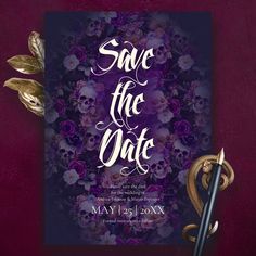 save the date card with purple flowers and gold leaves on it next to a pen