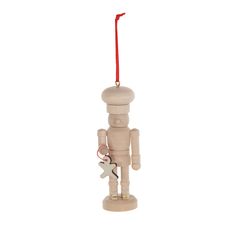 a wooden nutcracker ornament hanging from a red string on a white background