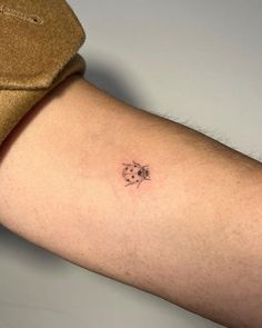 a person's arm with a small flower tattoo on the left side of their arm