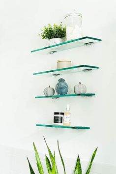 three shelves with plants and vases on them in the corner of a white bathroom