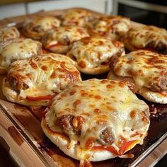 pizzas with cheese and meat are on a wooden tray in the kitchen, ready to be eaten