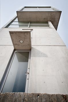 the corner of an apartment building with a window on one side and sky in the background