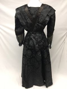 "1900s Edwardian Petite Black Silk Jacquard woven Taffeta Mourning Dress AS IS - FOR STUDY, Museum Deaccession Cannot be worn - Dress is a jacquard woven Black Silk Taffeta - A folded piece of Beige Crepe de Chine fabric has been tacked into front (not original) - Sleeves and edges are solid black silk satin - Sleeve cuffs are trimmed in black Silk crinkle chiffon, lined with beige birds eye netting - Bodice is lined in a heavy cotton chintz, which has stays and hook/eye closures in front - Deep Fitted Brocade Victorian Costume Dress, Vintage Brocade Dress With Historical Design, Black Victorian Dress With Fitted Bodice, Black Victorian Dress For Costume, Black Victorian Dress Costume, Victorian Style Black Costume Dress, Black Vintage Dress For Costume, Black Victorian Costume Dress, Black Brocade Dress For Formal Occasions