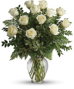 a vase filled with white roses and greenery