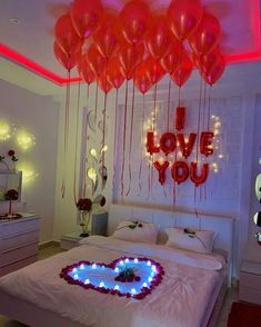 a bed with heart shaped balloons hanging from the ceiling