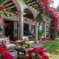 an outdoor living area with couches, tables and flowers